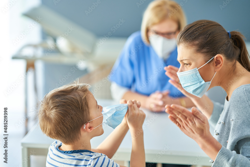 Mother with nervous son in child psychologist in mask Mother with nervous son in child psychologist in mask