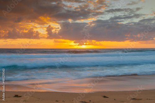 Sunrise at the seaside with waves and clouds