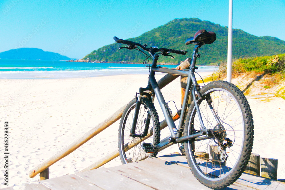 Bike on beach. Bike leaning at wooden fence at the beach, Praia Brava, Florianópolis, Southern Brazil Bike on beach. Bike leaning at wooden fence at the beach, Praia Brava, Florianópolis, Southern Brazil