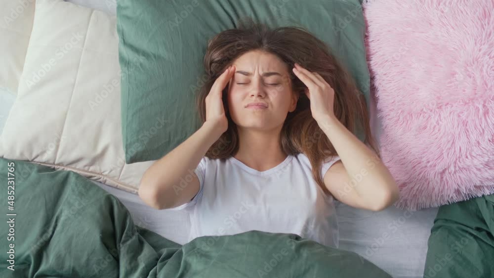 A Young Woman Wakes Up in a Bad Mood in an Bed At Home, Suffers from Headaches