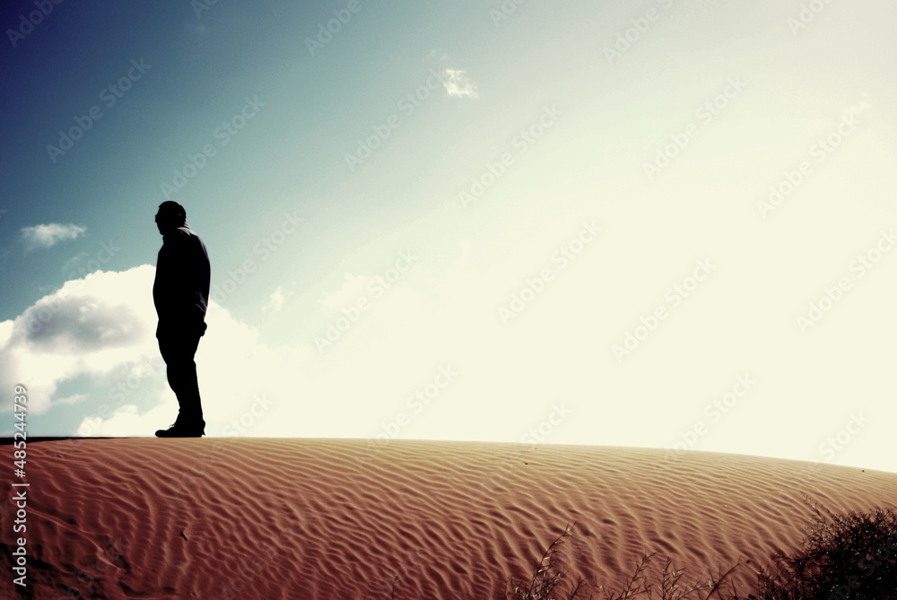 silhouette of a man walking on the sand