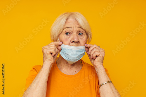 Portrait of an old friendly woman in casual t-shirt medical mask cropped view