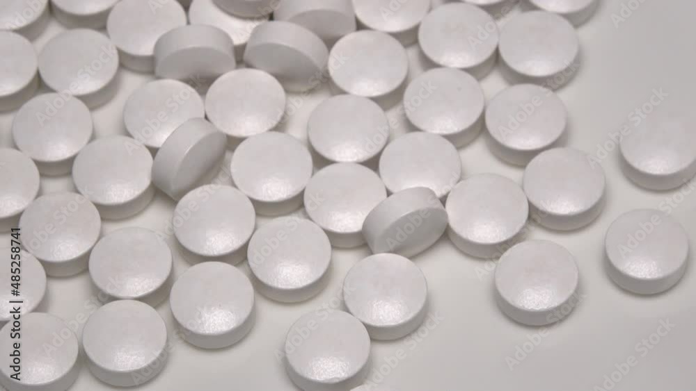 Closeup of many white medical pills rushing on a white plate. Medicine and dietary supplements. 4K resolution. Closeup of many white medical pills rushing on a white plate. Medicine and dietary supplements. 4K resolution.