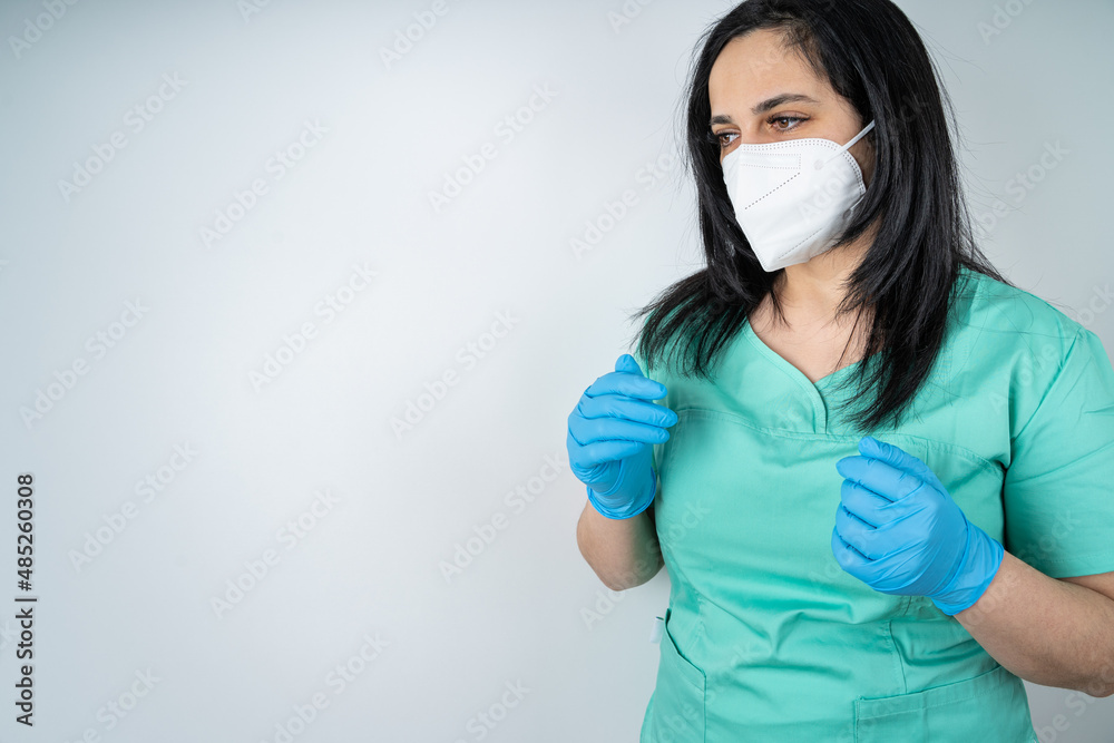 Nurse with face mask and blue medicine gloves bends her arms and looks to the side Nurse with face mask and blue medicine gloves bends her arms and looks to the side