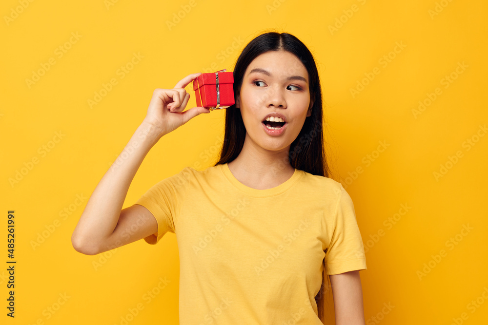 Charming young Asian woman in a yellow t-shirt holiday gift emotions studio model unaltered Charming young Asian woman in a yellow t-shirt holiday gift emotions studio model unaltered