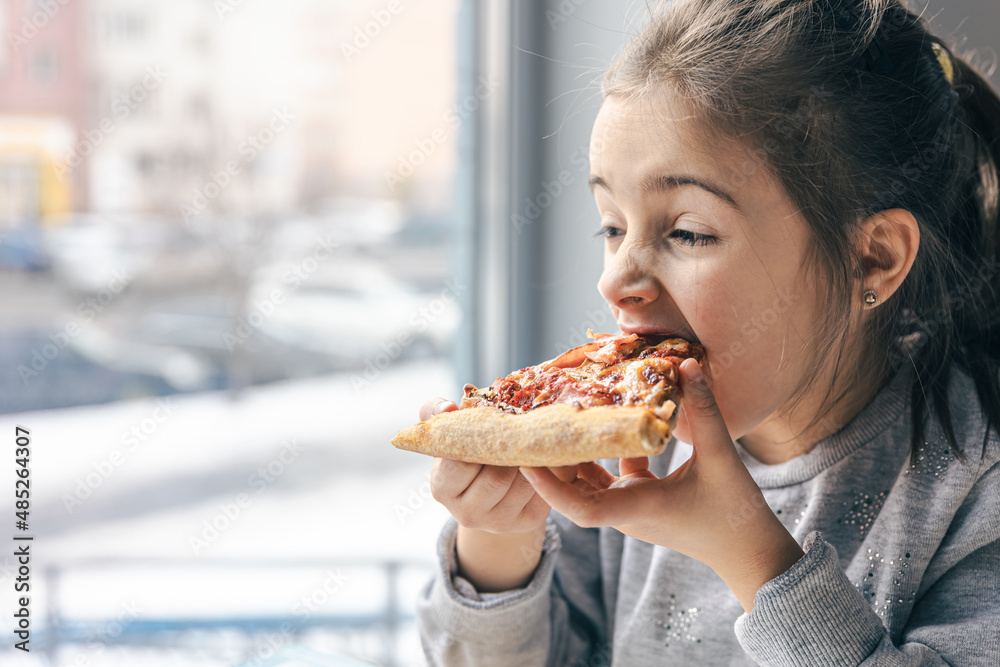 Portrait of a little girl with an appetizing piece of pizza.