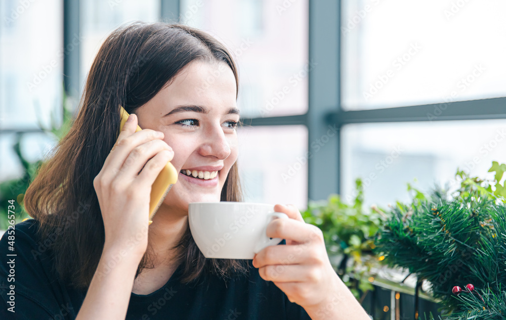Young woman talking on the phone while sitting by the window in a cafe. Young woman talking on the phone while sitting by the window in a cafe.