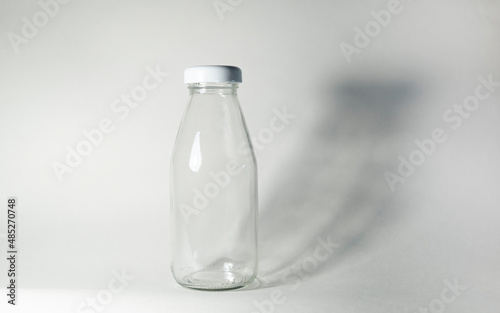 Glass milk bottle with a white lid on a white background