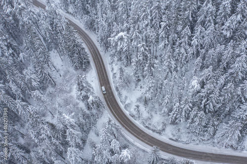 Snowy Winding Curving Mountain Road with Moving Car During Snowfall