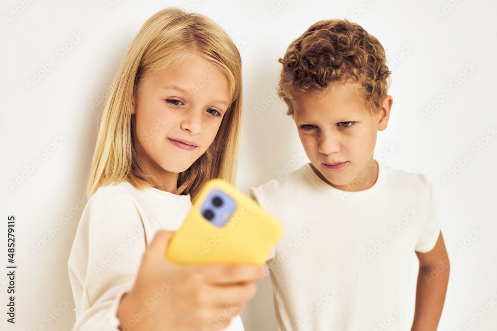 Two preschool children boy and girl looking at the phone posing lifestyle childhood Two preschool children boy and girl looking at the phone posing lifestyle childhood