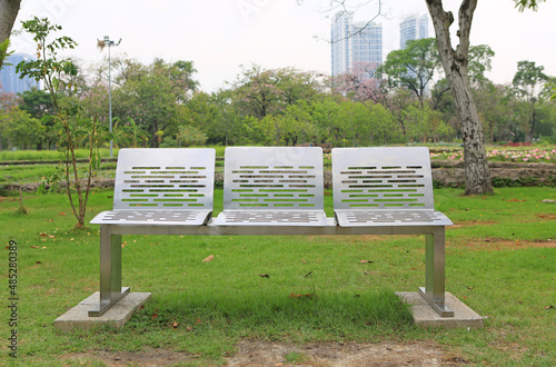 Modern stainless chairs in the public park with fall dried leaves around.