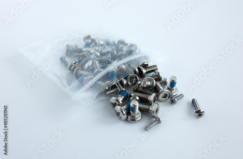 Small silver cogs on a white isolate. A plastic bag with screws for radio-controlled models. Chrome screws in a package on a white background. photo