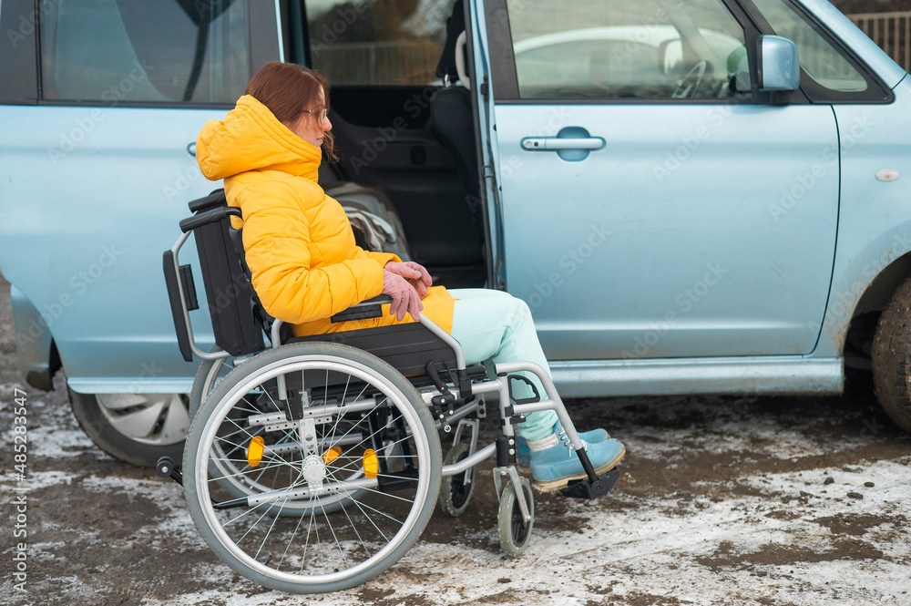 Caucasian woman in a wheelchair gets into the car. Caucasian woman in a wheelchair gets into the car.