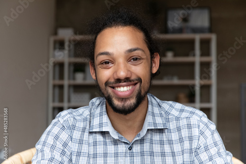 Head shot happy millennial generation African American bearded man looking at camera, holding pleasant distant video call conversation, passing job interview remotely, web camera screen view.