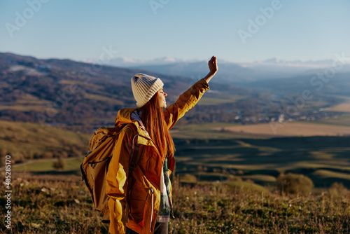 woman tourist in a yellow jacket in a hat backpack travel mountains relaxation