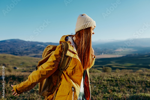 woman traveler in a yellow jacket in a hat backpack travel mountains Fresh air