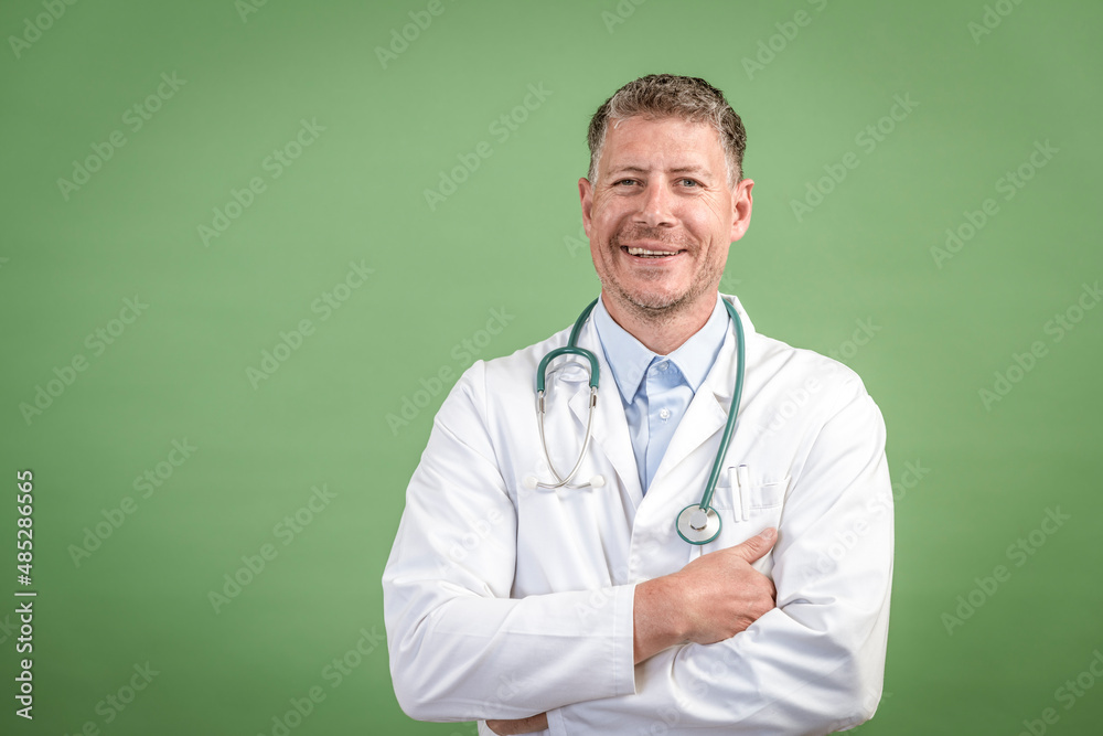 middle aged male doctor with grey hair wearing stethoscope and white coat on green background middle aged male doctor with grey hair wearing stethoscope and white coat on green background