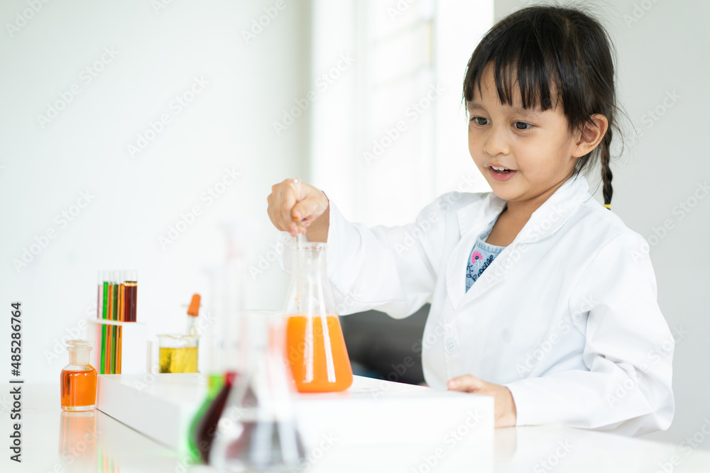 A little asian student is making experiment about the phase separation of oil and aqueous liquid in the flask at laboratory room, concept of chemical laboratory and science education for kid. A little asian student is making experiment about the phase separation of oil and aqueous liquid in the flask at laboratory room, concept of chemical laboratory and science education for kid.