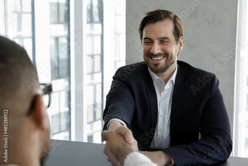 Schilderij op canvas Happy laughing business professional man and client shaking hands on meeting