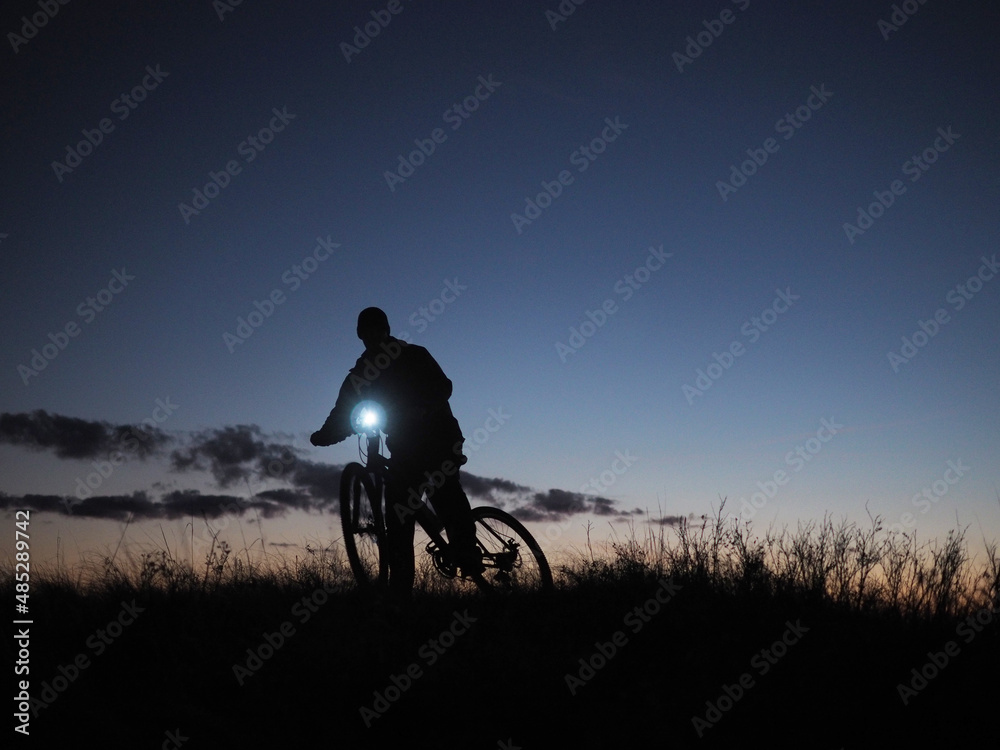 Obraz premium Silhouettes of a man on a bicycle against the background of the evening sky, after sunset.