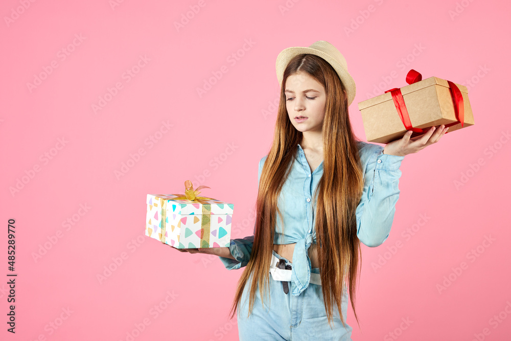Girl in jeans clothes and straw hat isolated on pink background. Valentine's Day, Women's Day, birthday concept. Hold present box with gift ribbon bow. Girl in jeans clothes and straw hat isolated on pink background. Valentine's Day, Women's Day, birthday concept. Hold present box with gift ribbon bow.