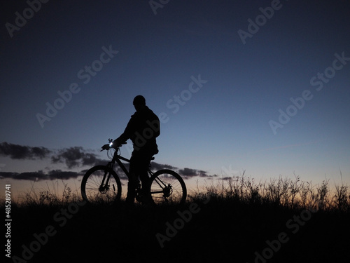Silhouettes of a man on a bicycle against the background of the evening sky, after sunset.
