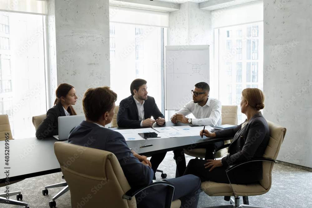 Diverse business group of company managers discussing marketing data, sales results at meeting table, reporting to African team leader. Investors, partners discussing startup project in office