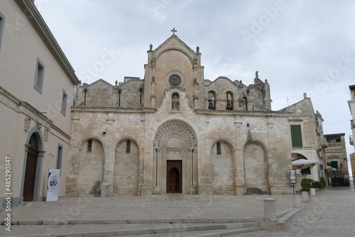 St. John Baptist church in Matera, the facade made by white sandstone with the decorated entrance door, the arches, the statues and the bells.