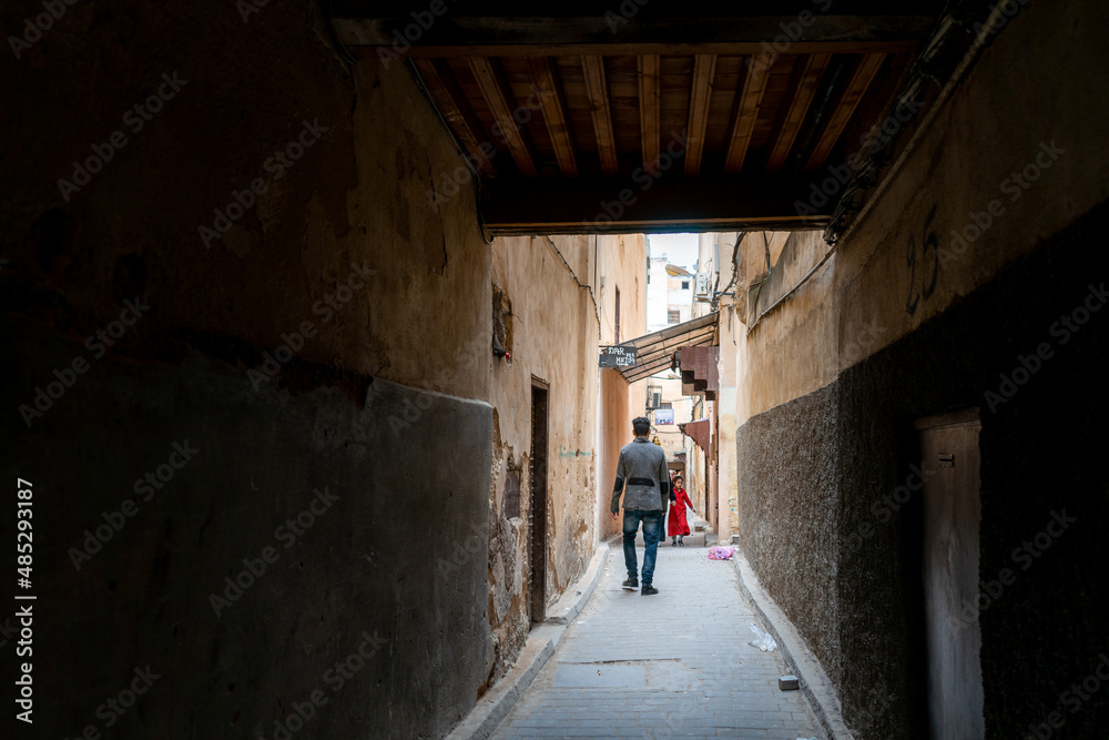 Man walks through a narrow street in the old medina of Fes