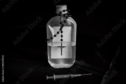 Bottle, needle and rosery front view on black background