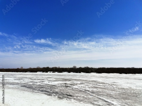 landscape with snowy river and blue sky in winter