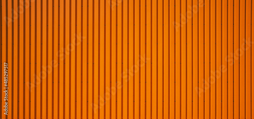 texture of an orange corrugated sheet metal facade. Close up of an exterior wall of a warehouse in the industrial area.