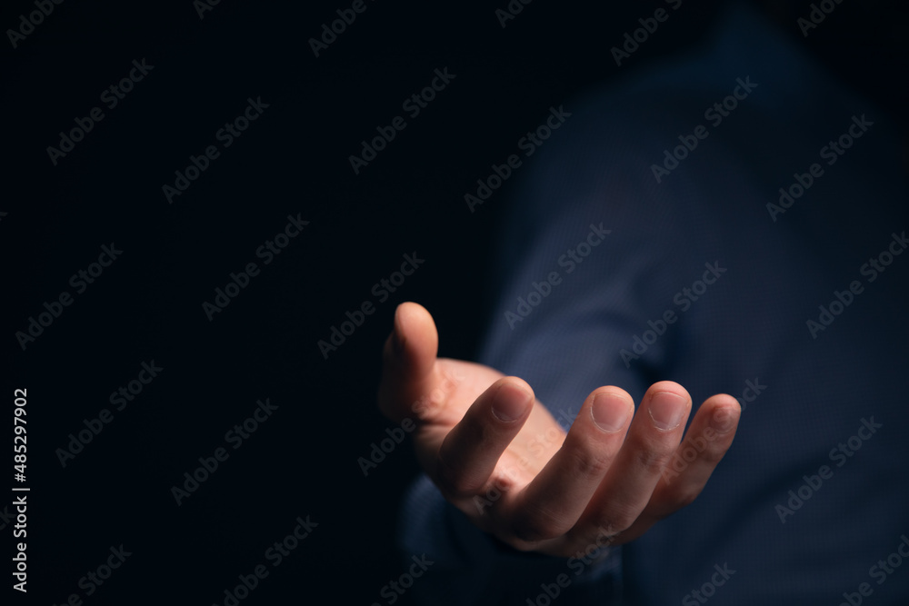 Businessman with empty hand on dark background Businessman with empty hand on dark background