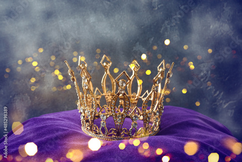 Golden queen crown over mysterious dark background. Mythical or fantasy world concept