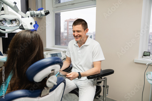 Dentist communicates with patient in dental office using digital tablet