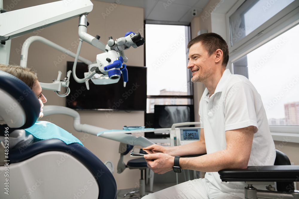 Dentist communicates with patient in dental office using digital tablet Dentist communicates with patient in dental office using digital tablet