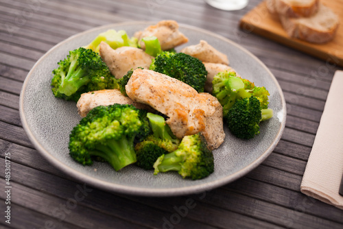 pieces of fried chicken breast with boiled broccoli on plate for breakfast