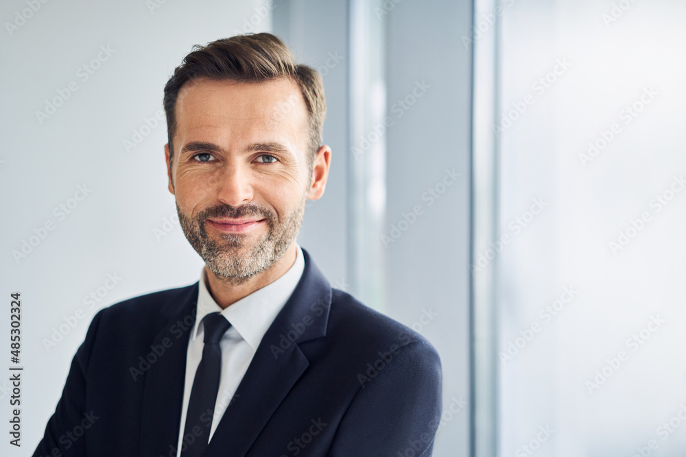 Portrait of smiling businessman standing in office looking at camera - obrazy, fototapety, plakaty 