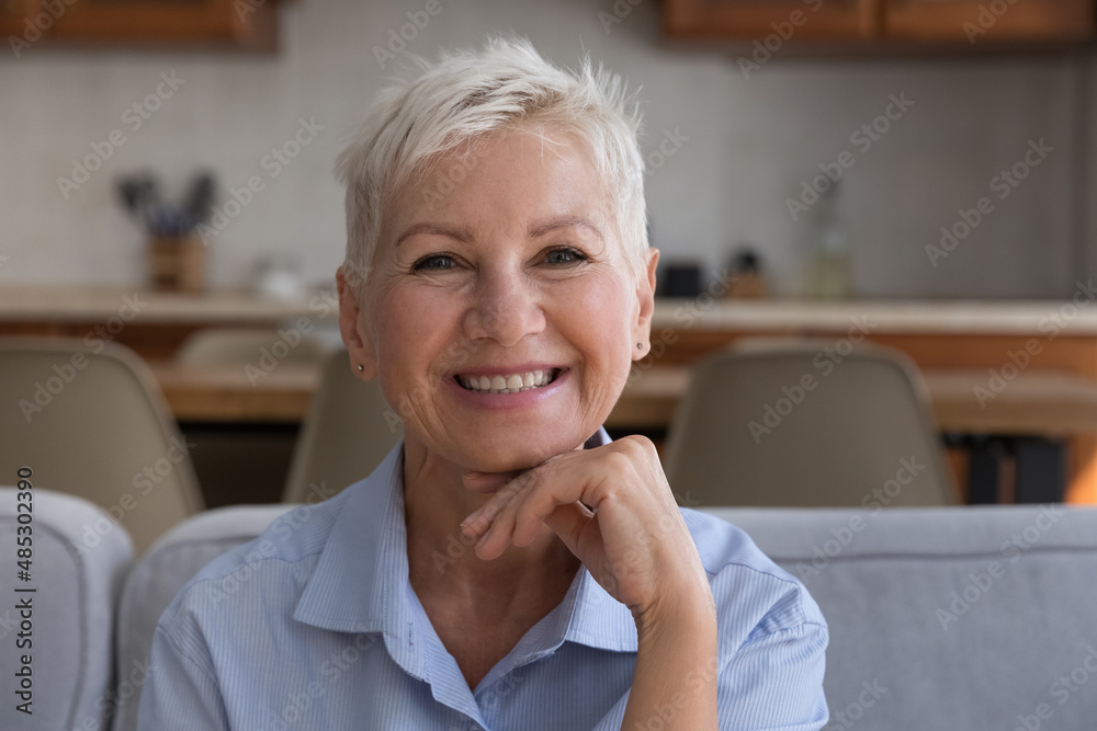Happy stylish senior 60s woman home head shot portrait. Cheerful blonde short haired middle aged lady in casual looking at camera with toothy smile, posing, laughing. Video call screen Happy stylish senior 60s woman home head shot portrait. Cheerful blonde short haired middle aged lady in casual looking at camera with toothy smile, posing, laughing. Video call screen