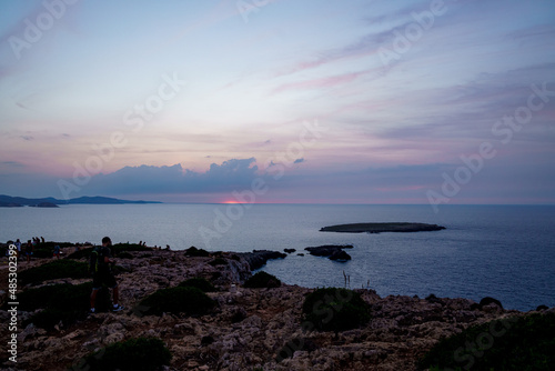 Far de Cavalleria, Menorca. September 2021. People enjoying the wonderful sunsets over the sea from the island of Menorca.