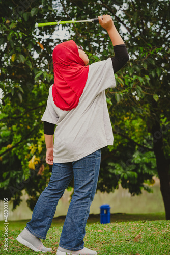 Young hijab Asian girl playing badminton at the park.