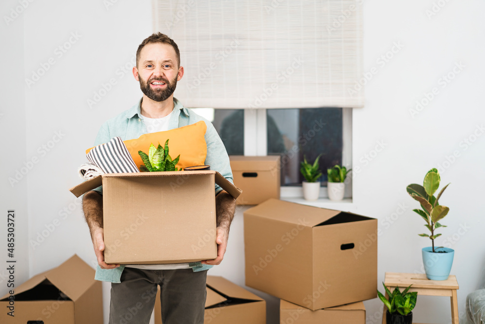 Mature man carrying a moving box with cushions, moving into new apartment Mature man carrying a moving box with cushions, moving into new apartment