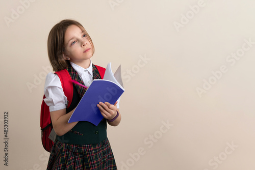 Businesslike Little Girl 9s wearing school uniform writing down her ideas in planner, holding notebook diary. Child have excellent idea. Time-management. photo