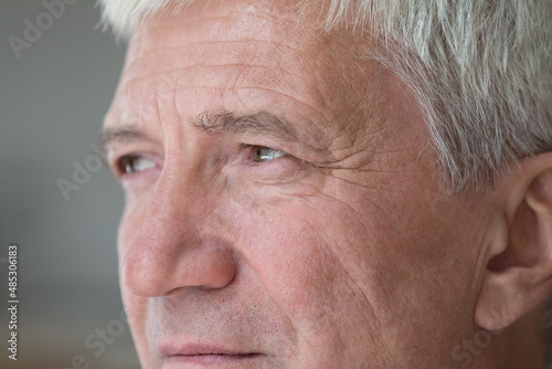 Serious thoughtful senior middle aged man looking away in deep thought. Mature retiree face with brown eyes, wrinkles close up. Elderly age, healthcare, vision, eyesight concept. Cropped shot