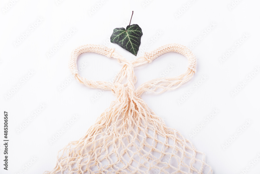 Fototapeta premium Eco friendly string bag and green leaf on white background, responsible consumption. zero waste concept.