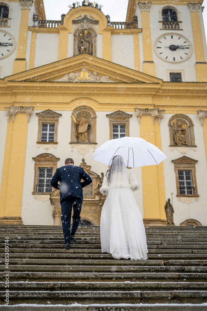 bride and groom go up the church steps, winter wedding