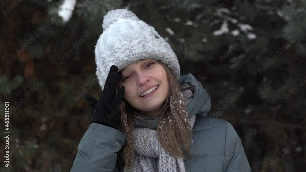 a pretty girl in winter clothes wipes her face from the snow against the background of the forest. High quality 4k footage a pretty girl in winter clothes wipes her face from the snow against the background of the forest. High quality 4k footage