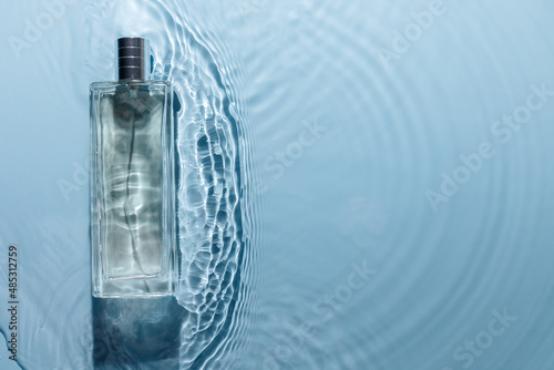 Perfume bottle on blue water wavy background. Fresh sea fragrance concept. Pure