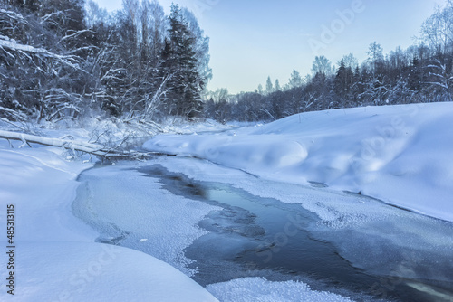 Snow banks of forest river at winter sunset. Winter landscape © Roman