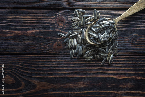 Fototapeta Naklejka Na Ścianę i Meble -  Sunflower seeds in a wooden spoon on a dark wooden background